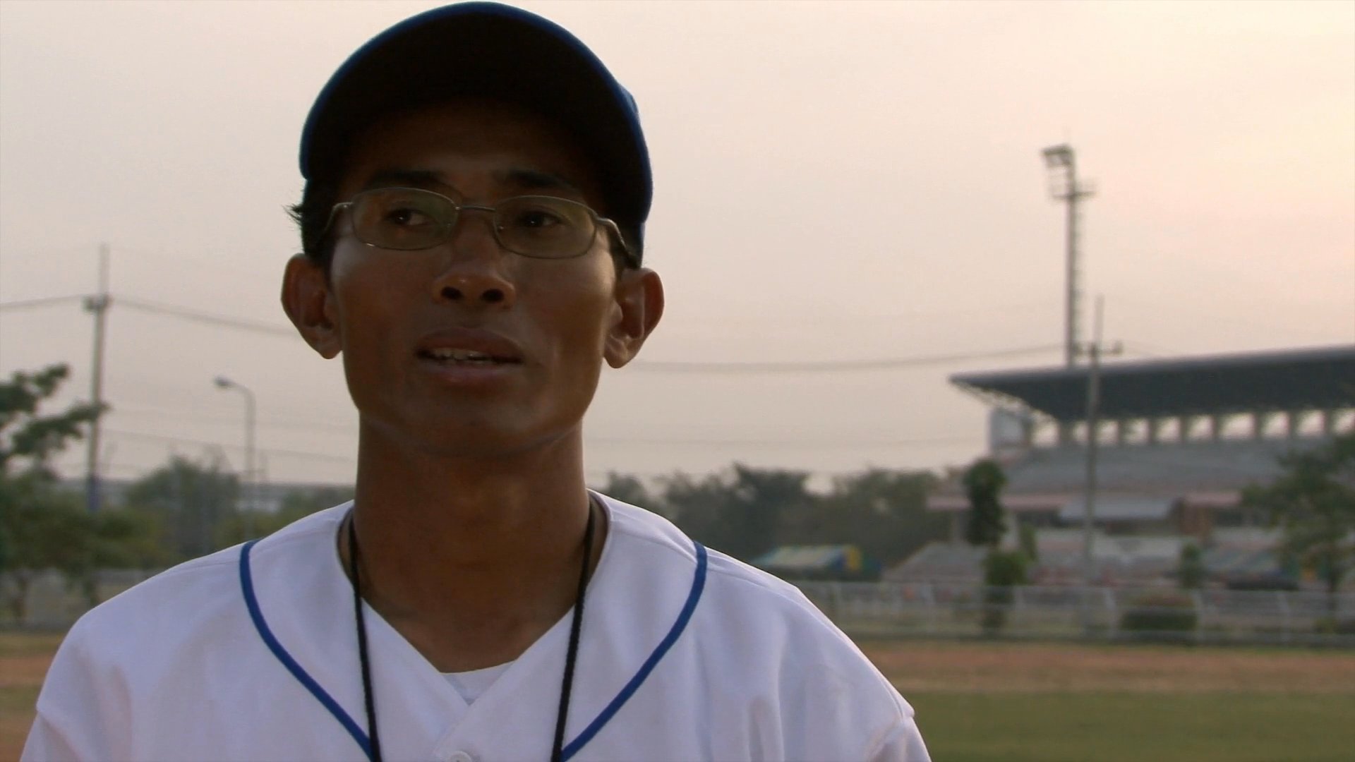 A baseball coach discusses his efforts to develop the sport and demonstrate athletic talent within Cambodia at a stadium training facility.