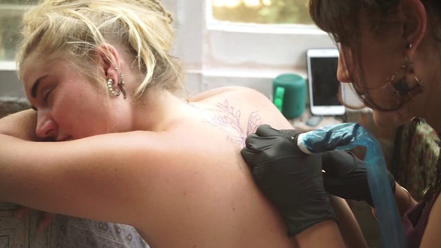 Woman getting a back tattoo