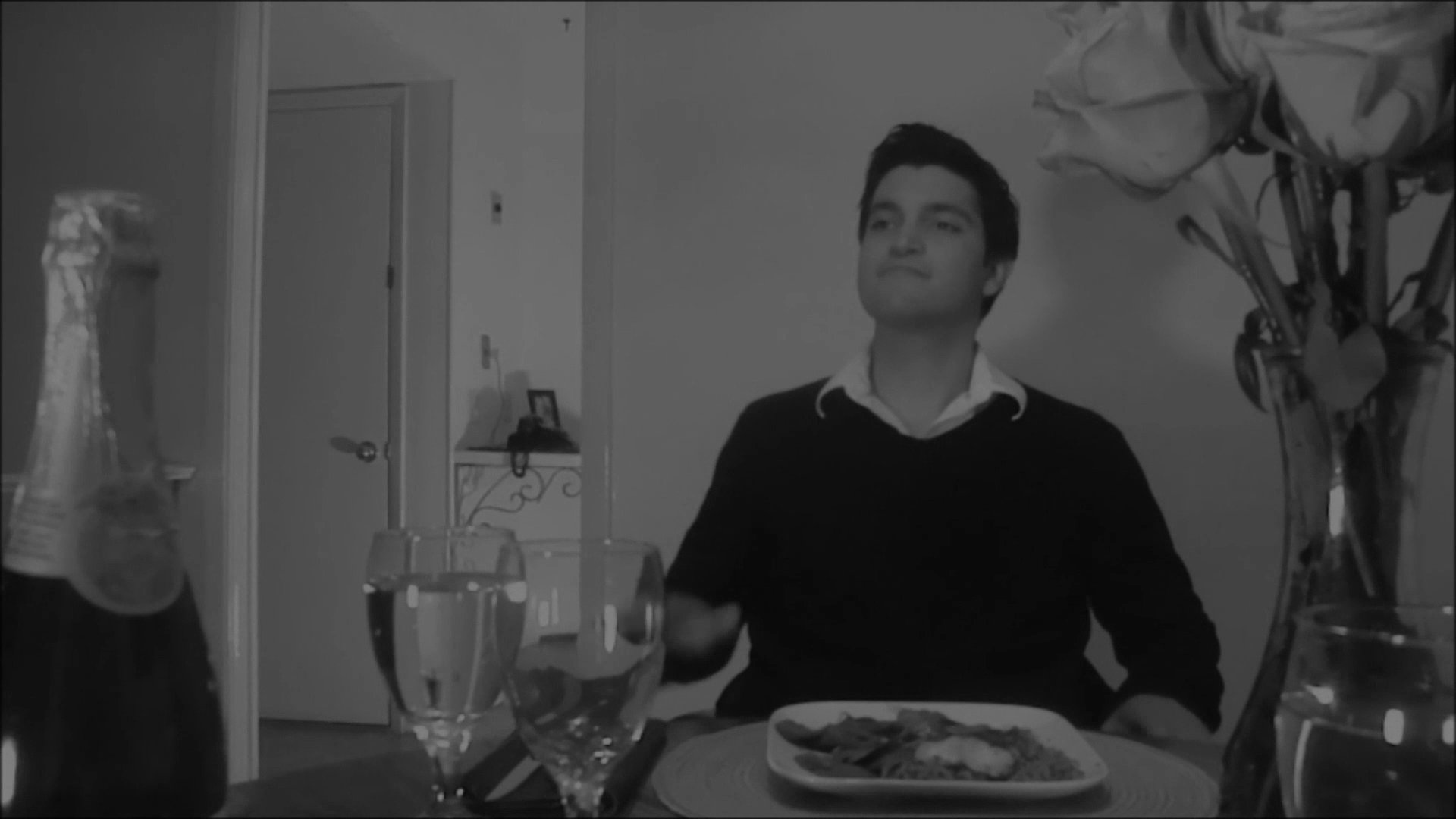 A man sits alone at a dining table, checking a wall clock while waiting for a guest. His restless behavior reflects growing impatience and anticipation over the course of the meal.