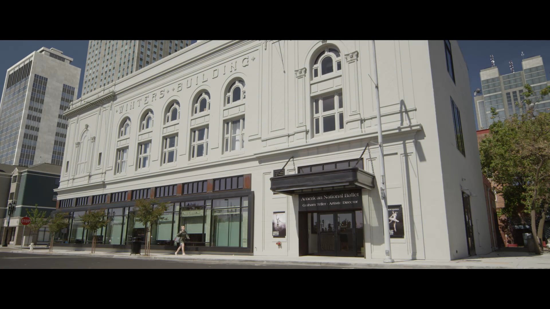 An exterior view of the historic American National Ballet building transitions to an interior reception area where a visitor arrives for an appointment.
