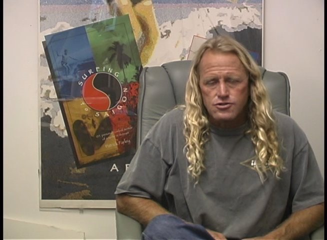 Filmmaker Pat Farley sits for an interview and discusses his professional experiences and insights into the craft of filmmaking. He provides commentary while seated before a background featuring a Surfing posters.