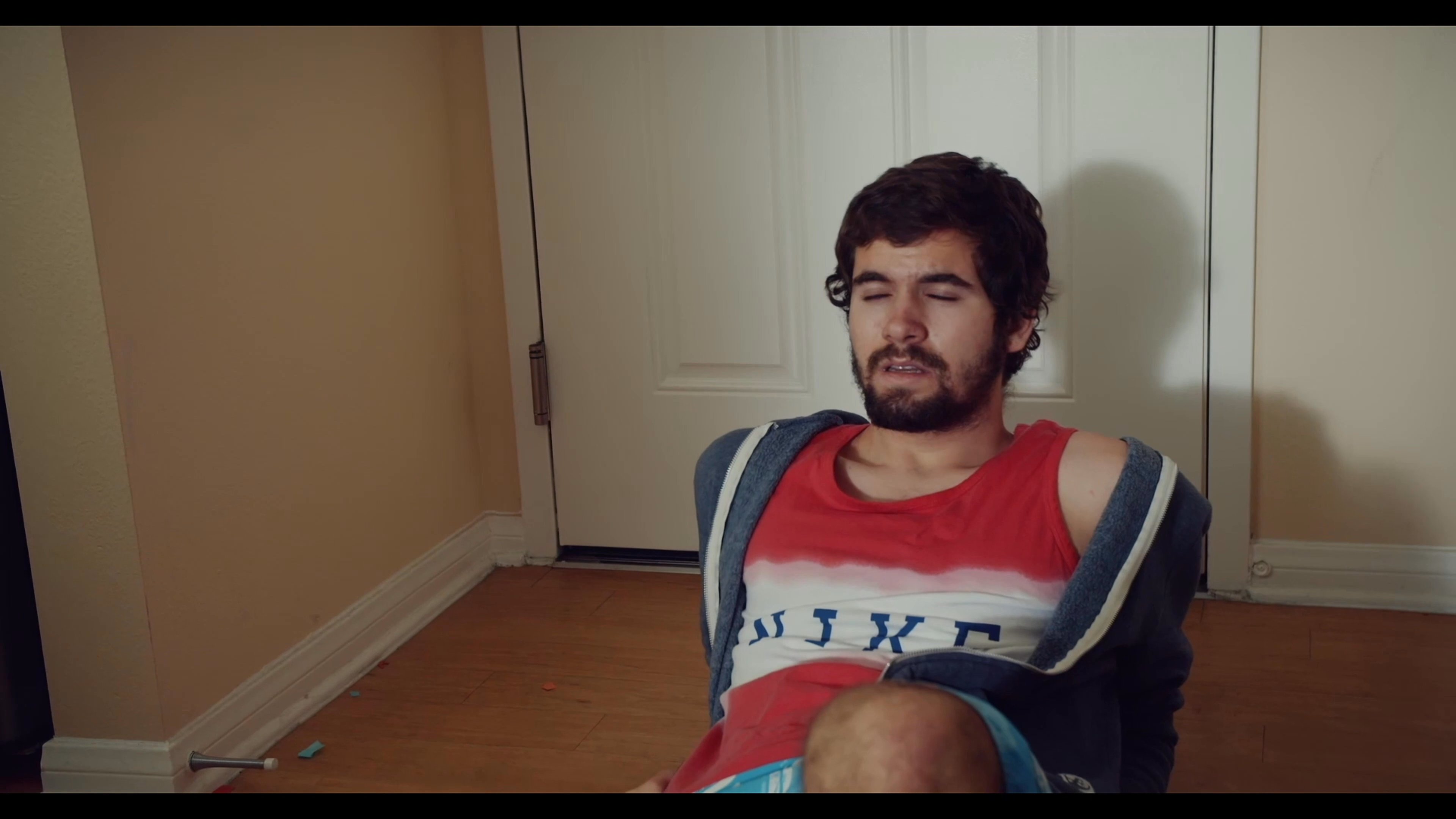 A group of young men engage in a lighthearted prank involving darts, resulting in humorous reactions and shifting between a kitchen and living room setting.