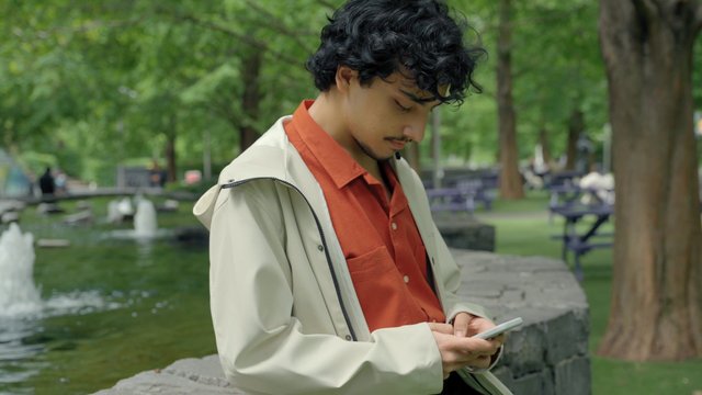 A guy uses a smartphone in a park