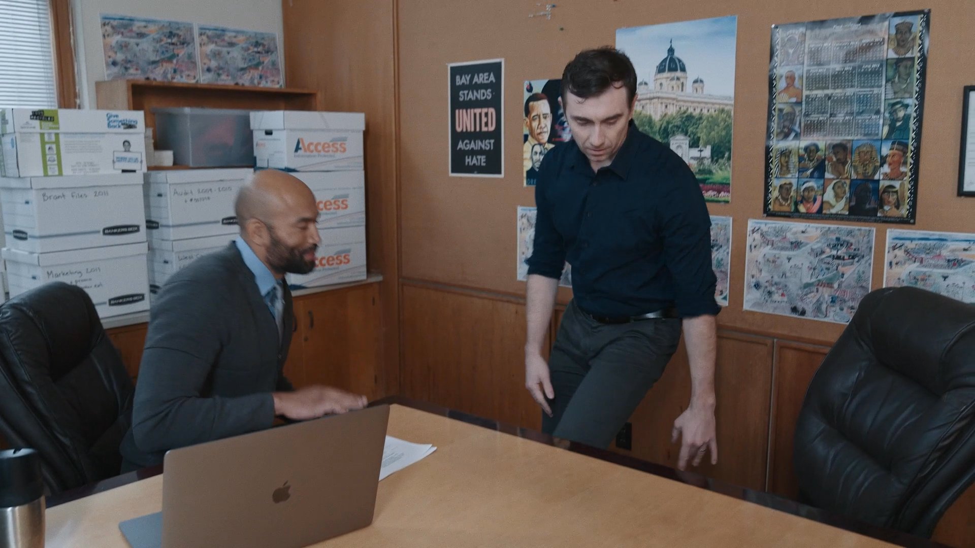 Two professional colleagues conclude a meeting and stand up to depart from their shared office space.