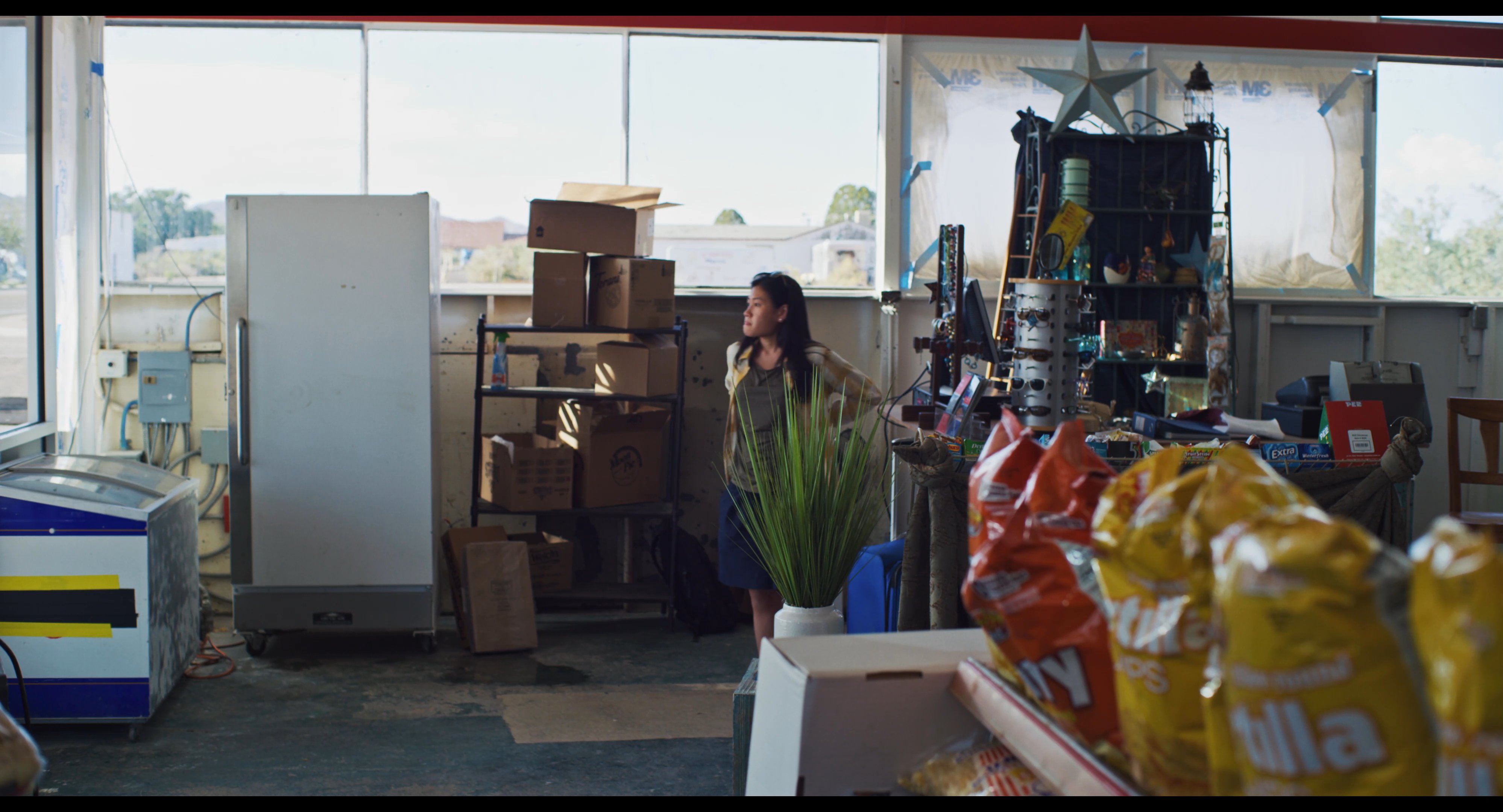 A woman examines a large paper map inside a store before engaging in conversation with a clerk.