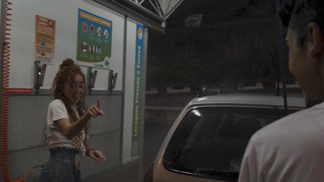 Man spraying woman with water at car wash