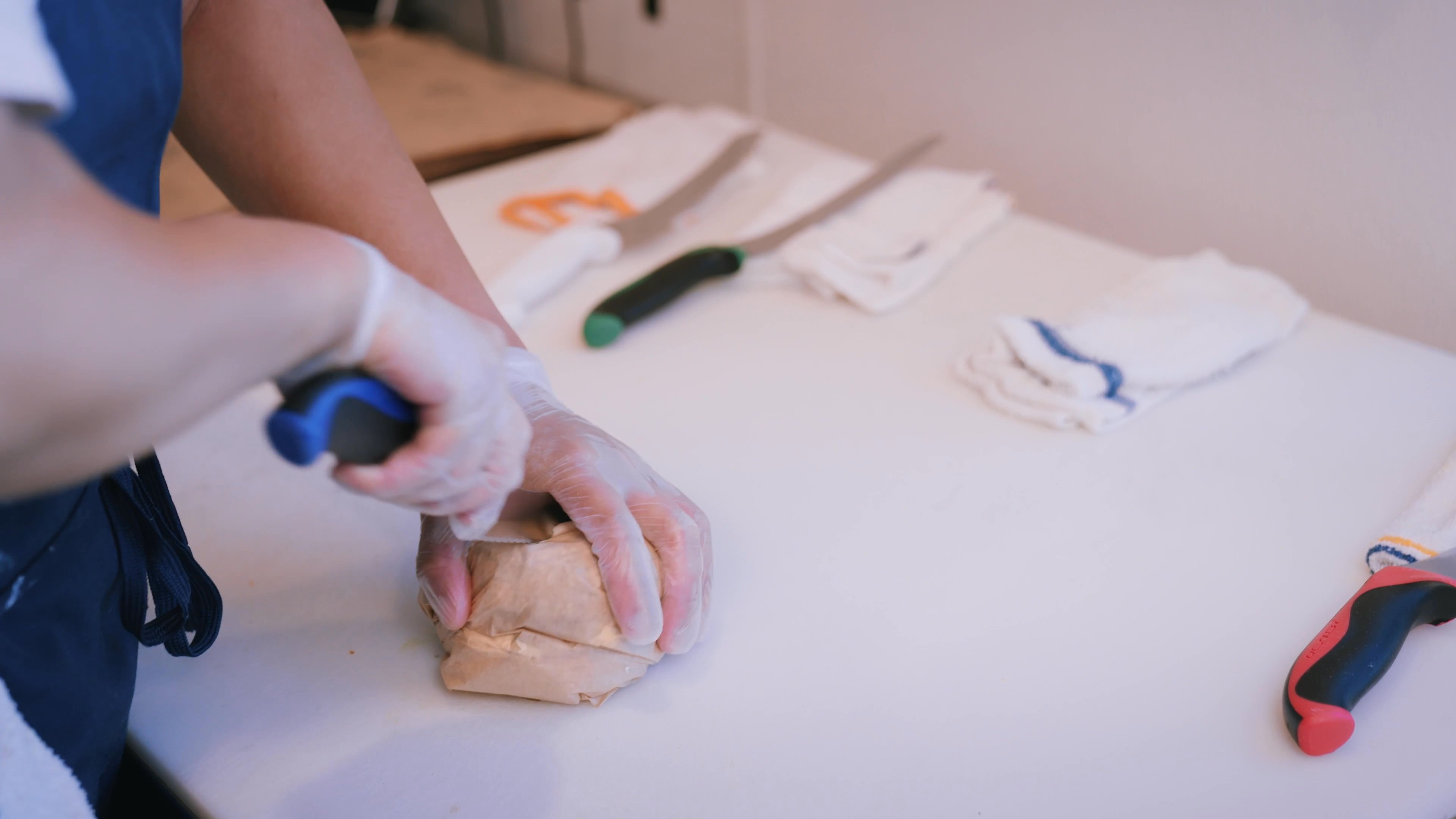 A food service worker assembles a salmon bagel sandwich, wraps it in paper, and packages orders for customers in a professional deli environment.