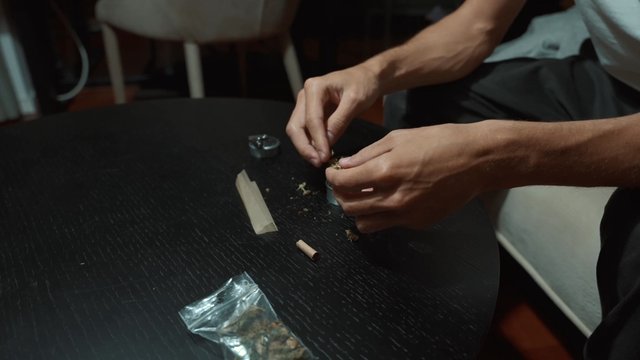 A man filling a herb grinder with cannabis