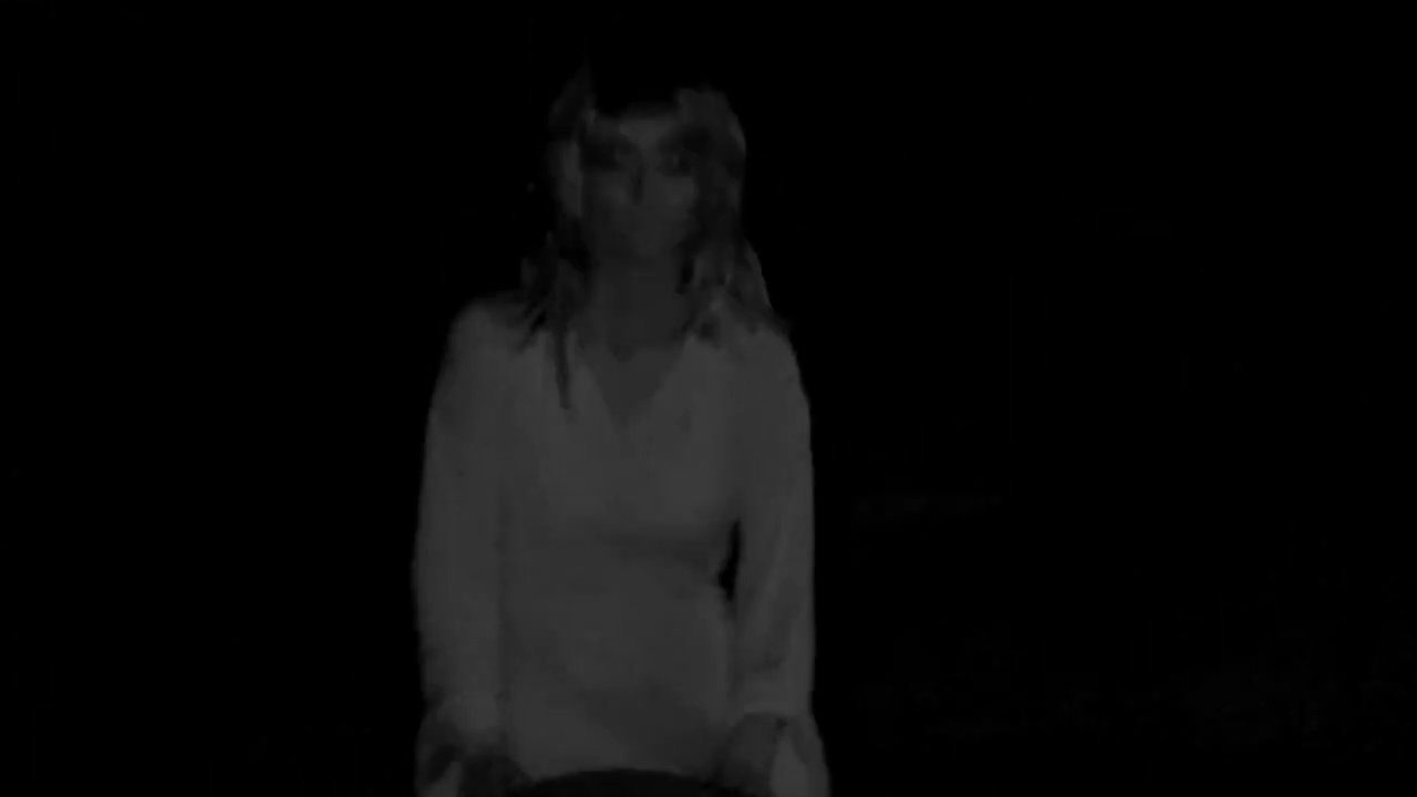 A woman conducts a night vision investigation in a cemetery, transitioning to a display of a historical group photograph featuring soldiers.