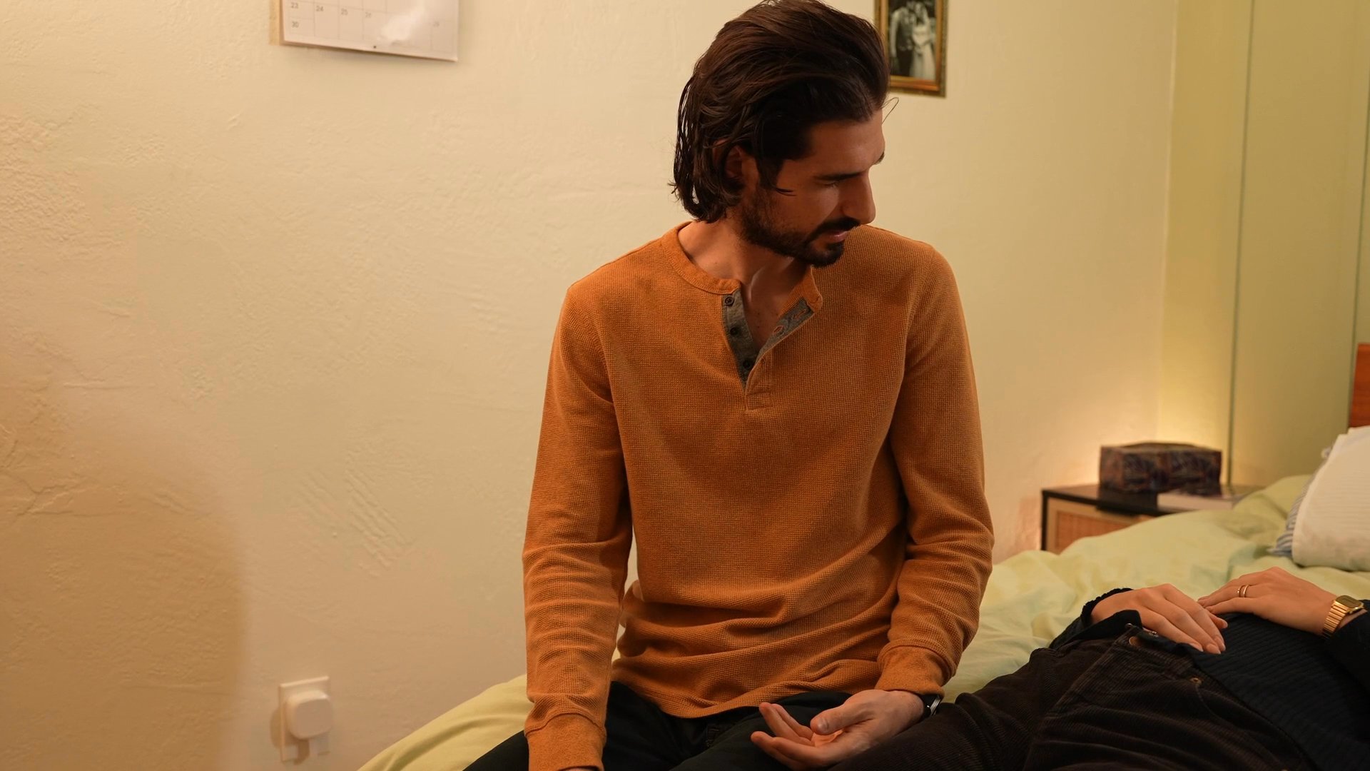 A group gathers for a Thanksgiving dinner before the focus shifts to a man and woman having a serious, private conversation in a bedroom. The sequence contrasts festive public social interaction with intimate, potentially strained interpersonal dialogue.