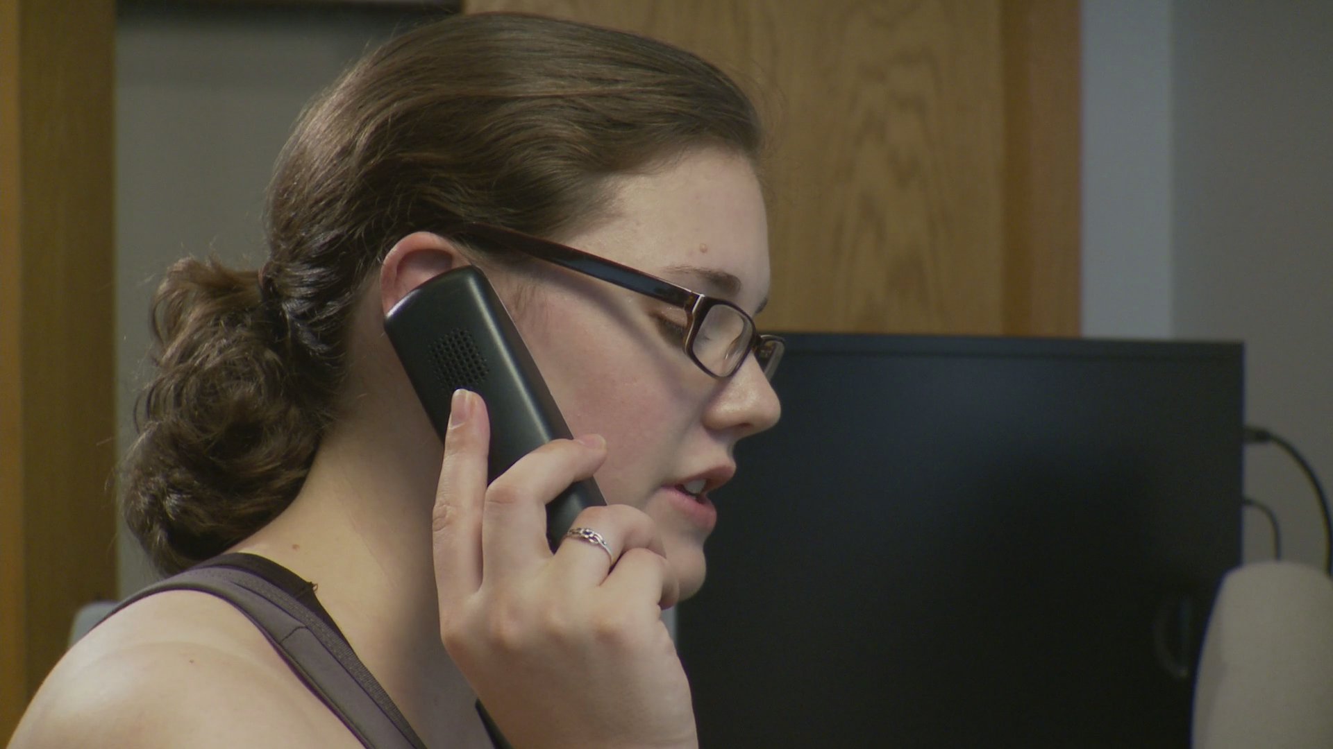 Two individuals engage in separate, intense telephone conversations within their respective professional environments. The visual sequence alternates between a young woman speaking on a phone and an older man expressing emotional distress during his own call.