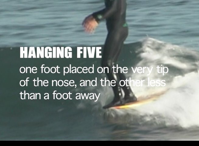 A surfer demonstrates classic longboarding techniques, successfully executing both a hanging five and a hanging ten maneuver on a wave.