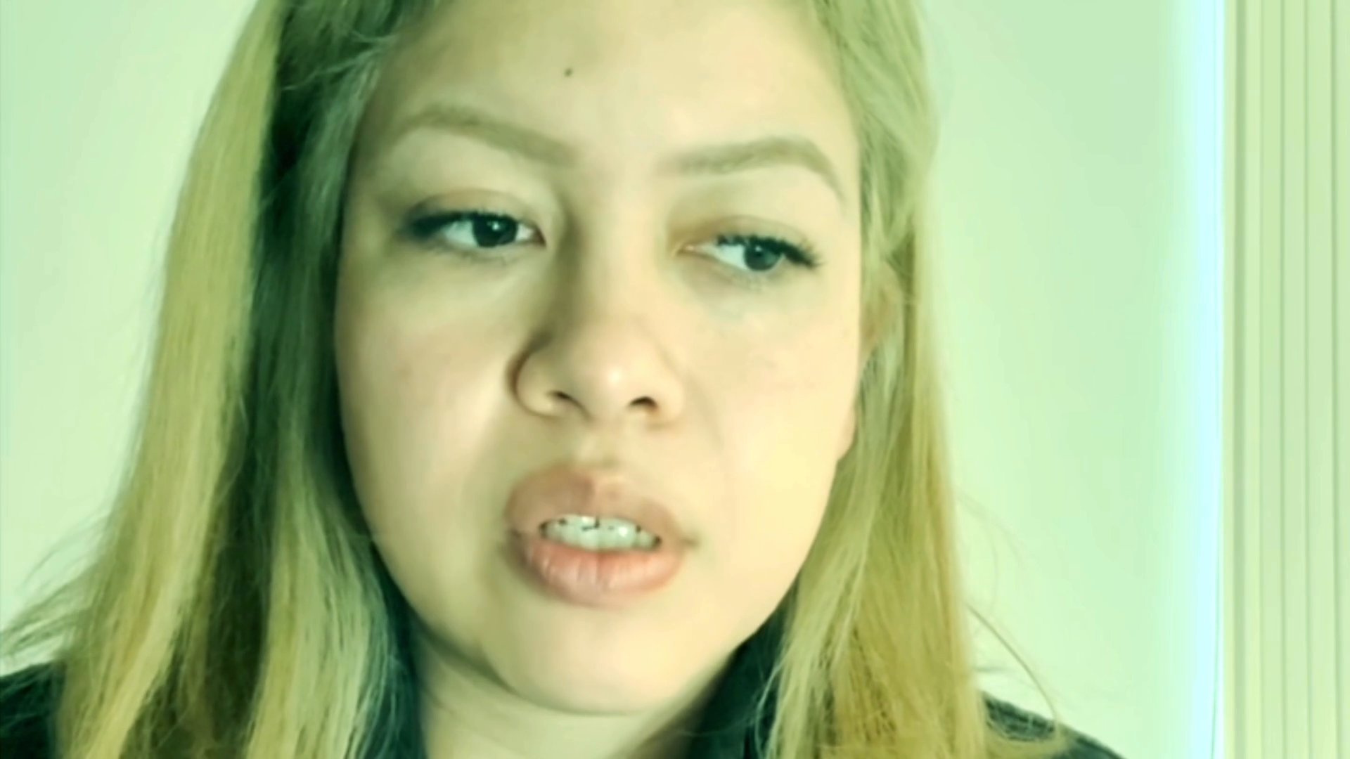 A woman speaks directly to the camera, conveying thoughtful expressions and subtle emotional shifts while sharing a narrative.