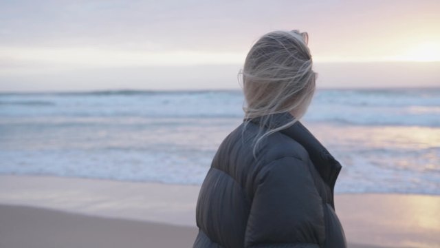 Blonde girl taking photos of the beach at sunset