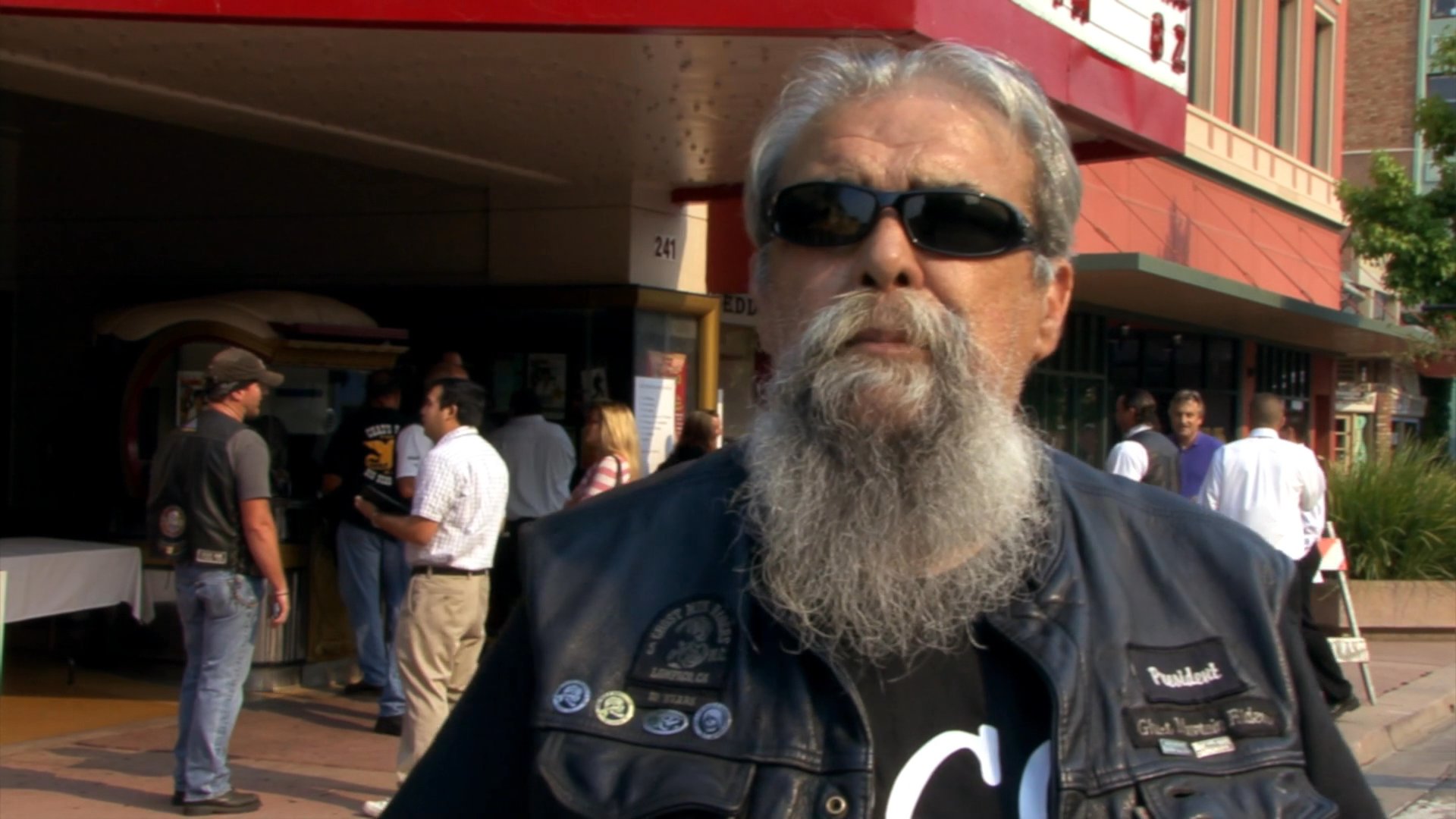 Members of the Ghost Mountain Riders motorcycle club discuss their organization during an on-location interview in front of a California theater.