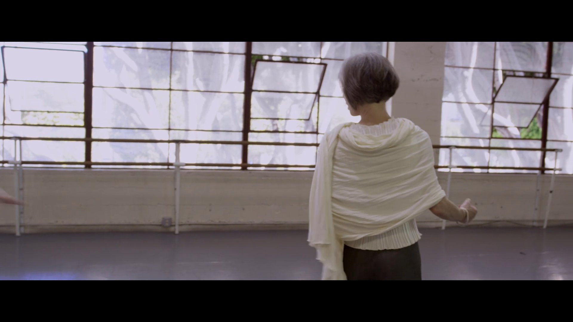 An experienced ballet instructor guides young students through dance technique and choreography in a professional studio setting.