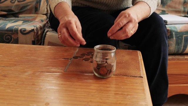 Woman putting coins in a jar 