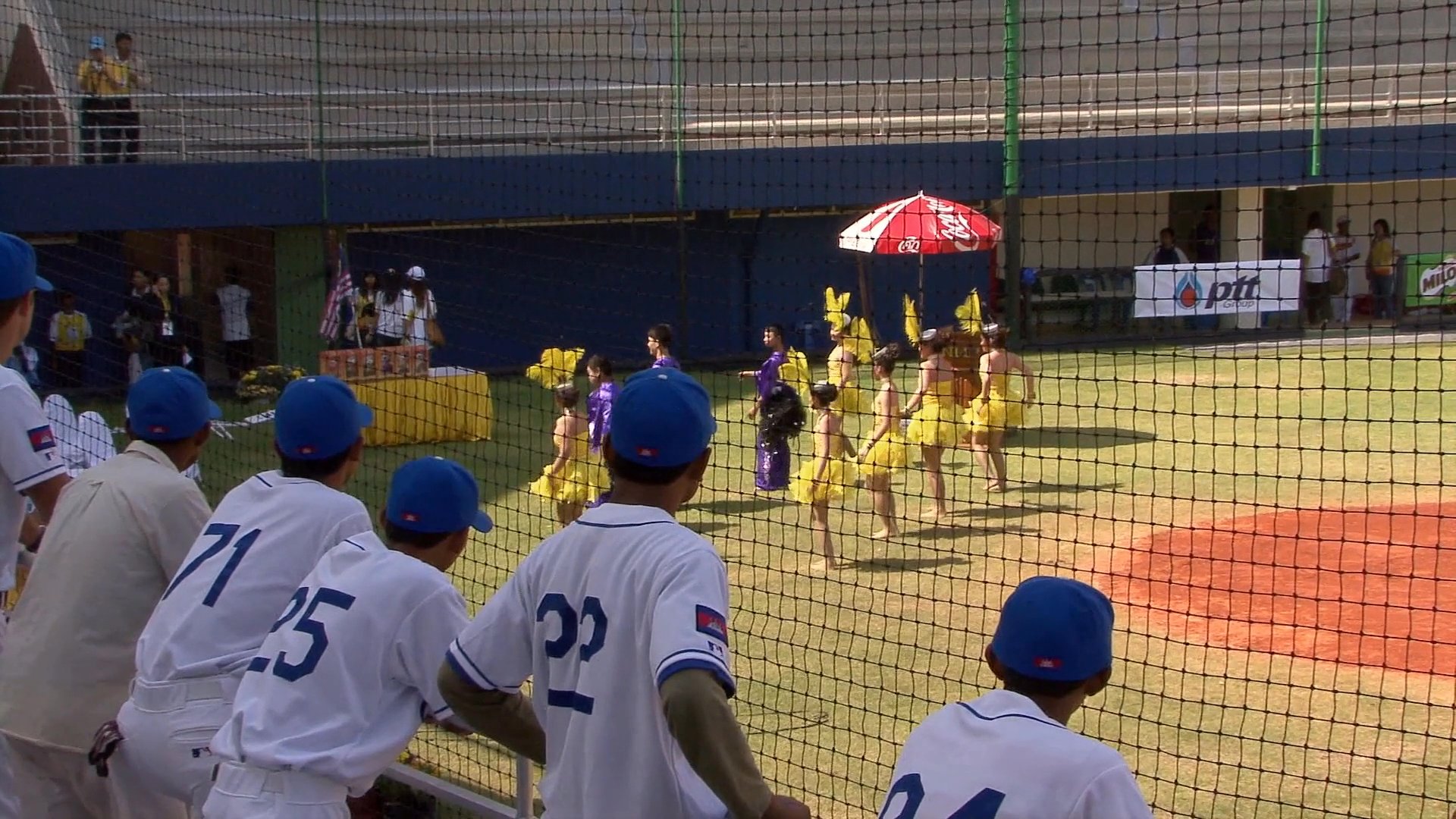 Members of the Cambodian baseball team celebrate during the 24th SEA Games while dancers perform on the field at the stadium in Nakhon Ratchasima.