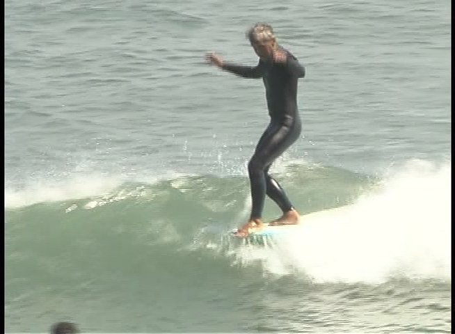 Surfers execute various crossing maneuvers and transitions while riding waves in the open ocean. Multiple individuals navigate the surf break in close proximity using longboards and shortboards.