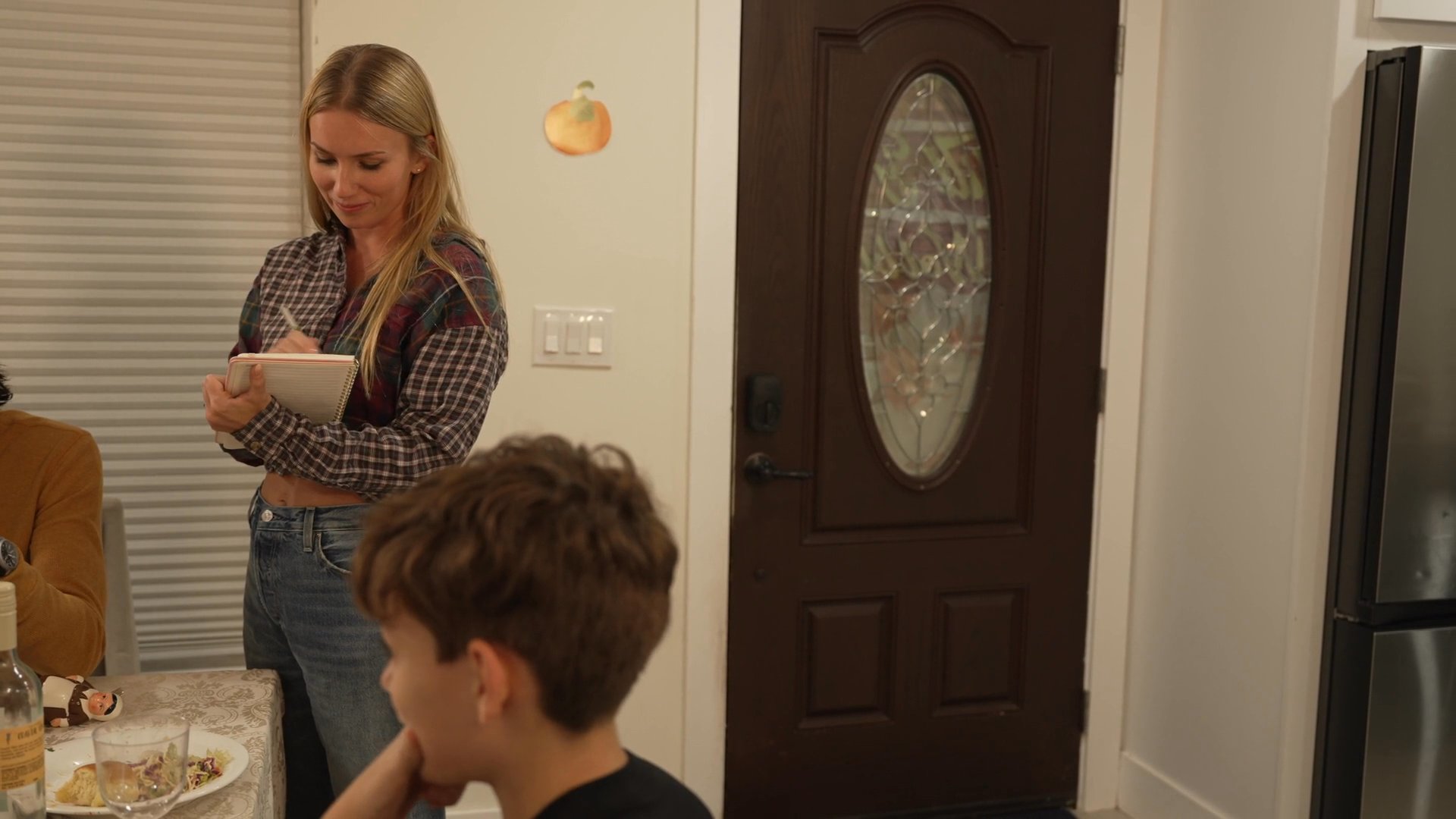 A woman hosts friends in a residential setting, greeting guests as they arrive for a dinner gathering.