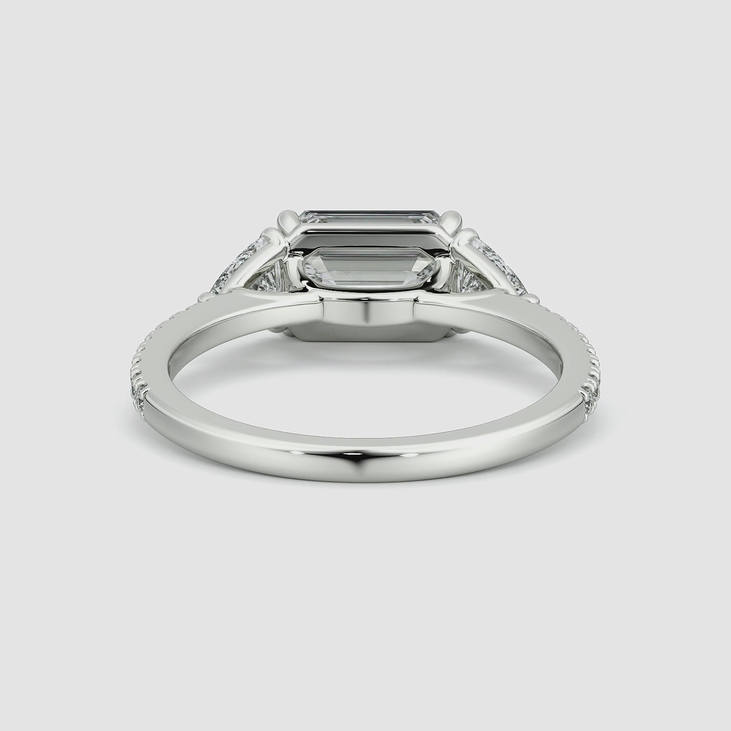 The Three Stone | Emerald | Platinum | bandAccent: Pavé | diamondOrientation: horizontal | sideStoneCarat: 0.25ct | sideStoneShape: Trillion | caratWeight: other