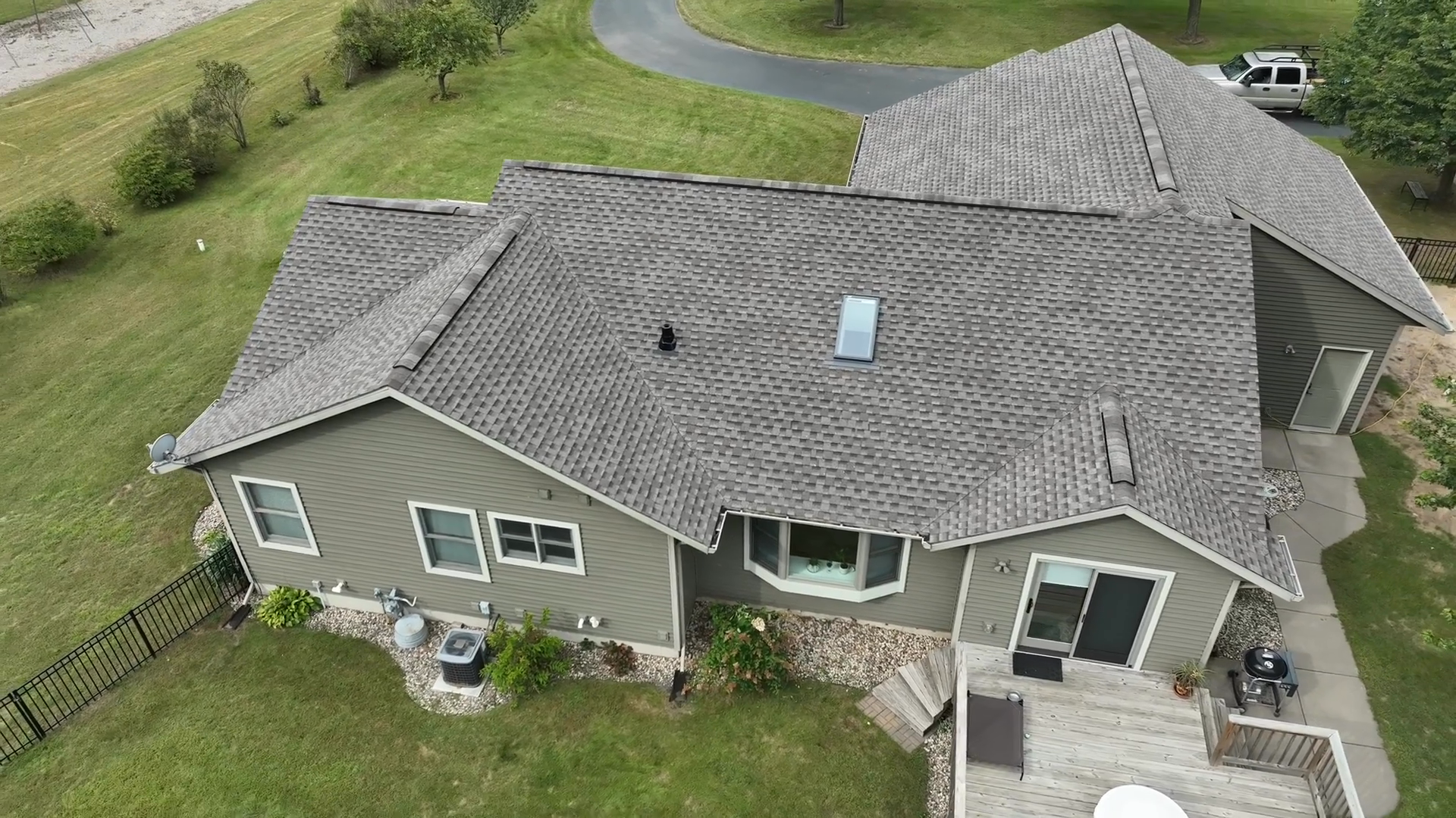Top-down aerial view of a gray shingled roof with a skylight and ridge vents