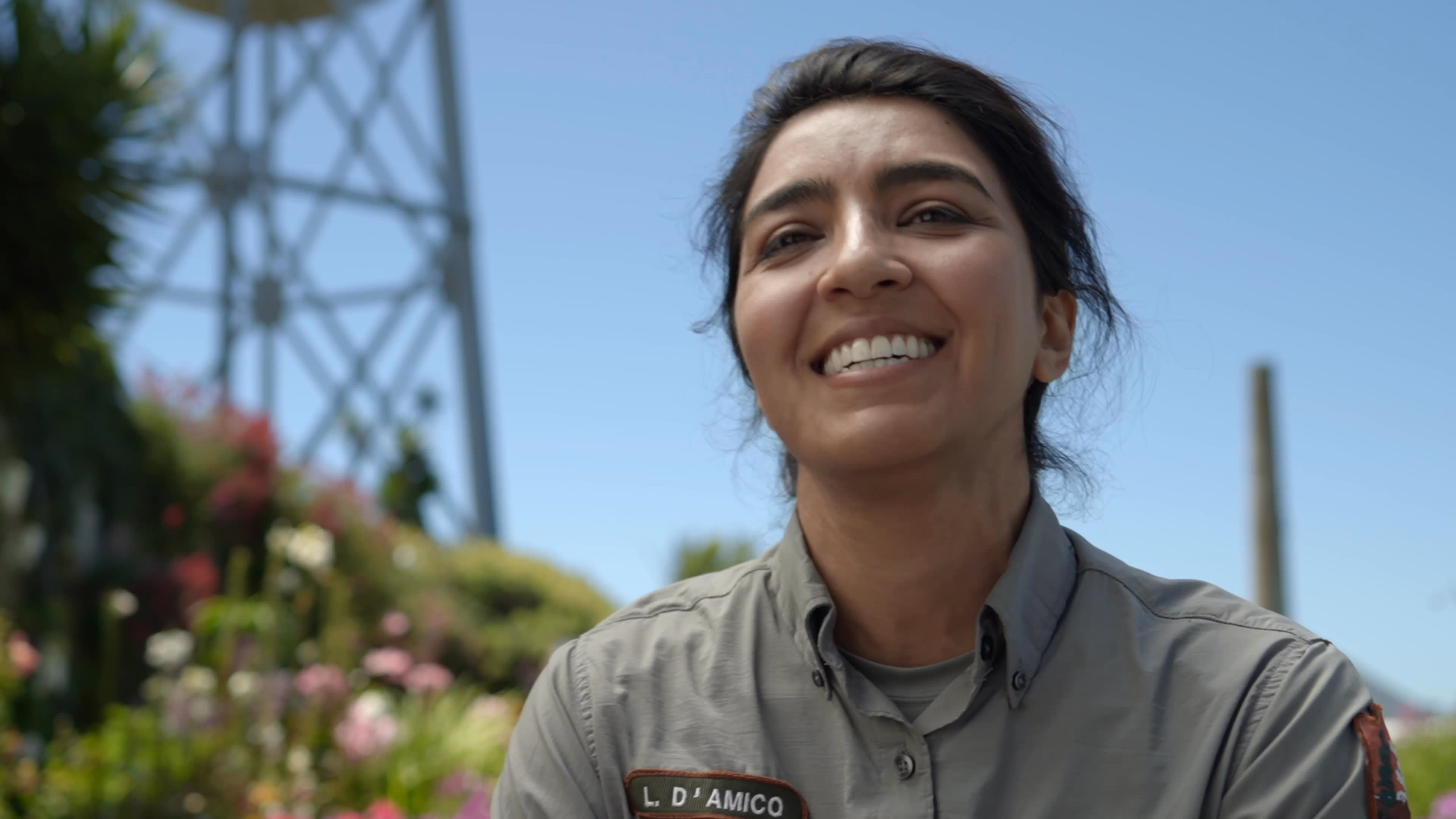 Wildlife biologist Lidia D’Amico describes the bird team on Alcatraz as staff walk the island and observe white birds among coastal shrubs. The team’s work unfolds against the bay and the island’s historic grounds.