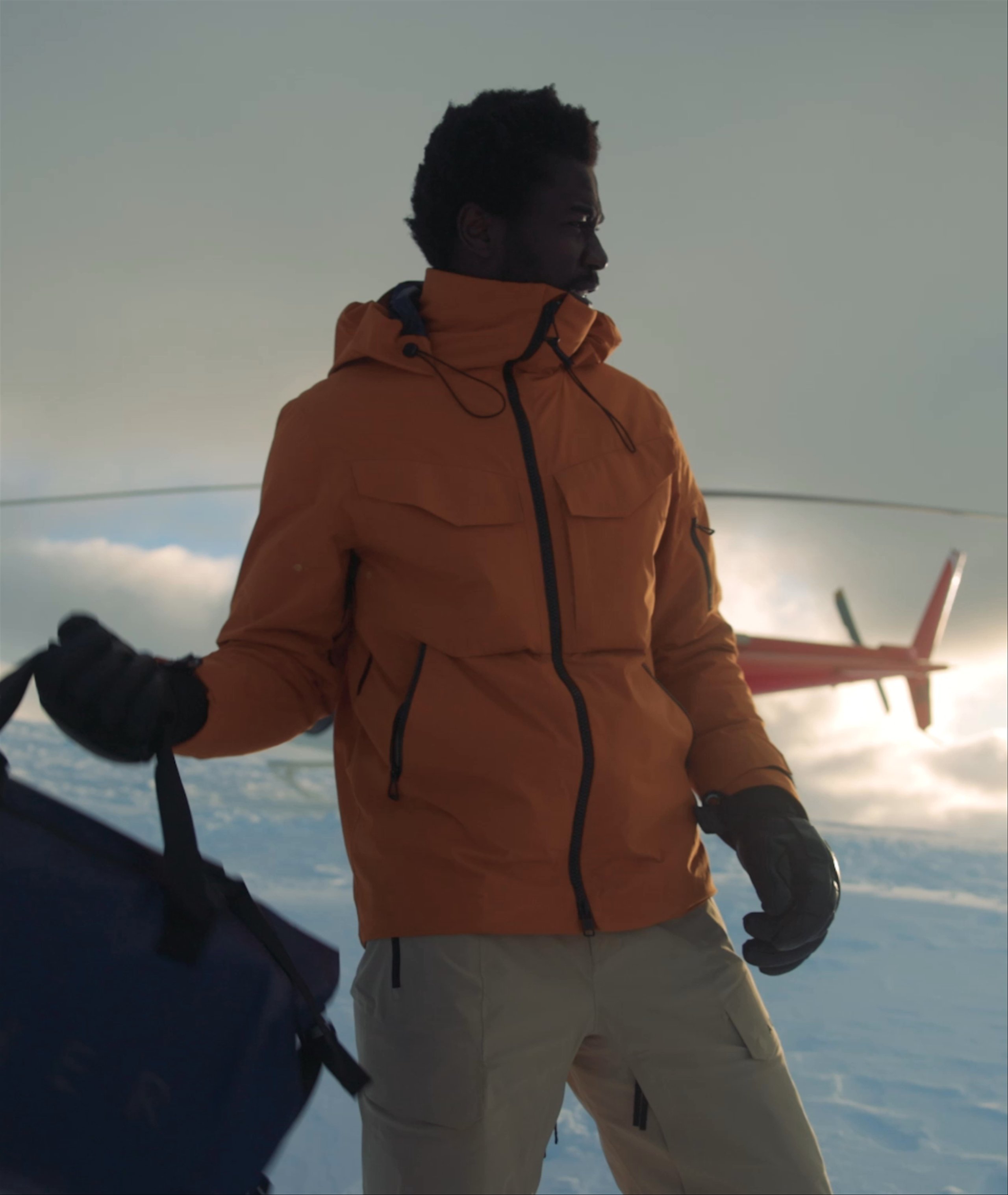 Video of man hoisting luggage over shoulder walking to helicopter on snowy mountain top