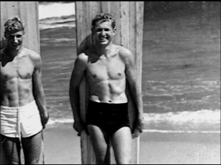 A transition from modern surfing on ocean waves to archival footage of historical beach culture. The sequence contrasts contemporary water sports with vintage portraits, highlighting the enduring nature of the surfing lifestyle.
