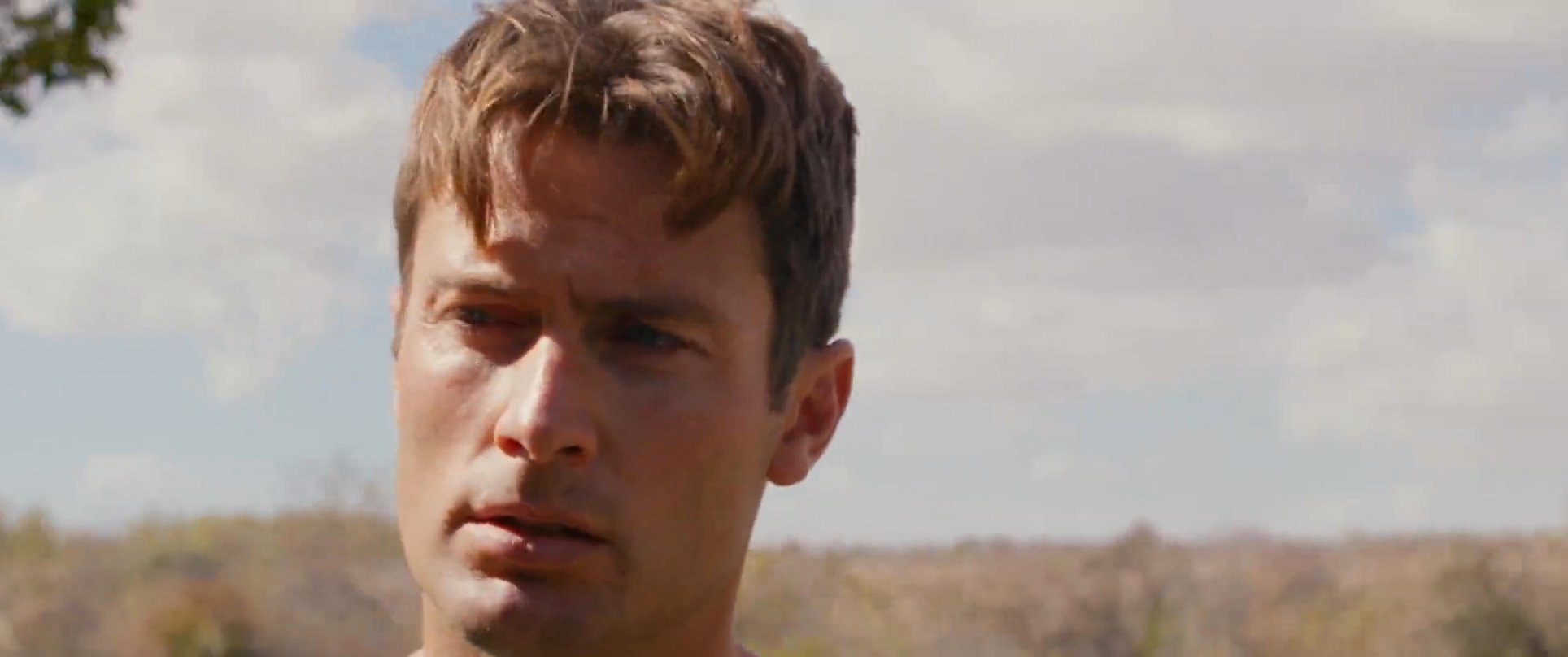 Two men engage in an intense, verbal standoff within a tree-filled outdoor setting. The interaction highlights significant personal tension as they exchange words.