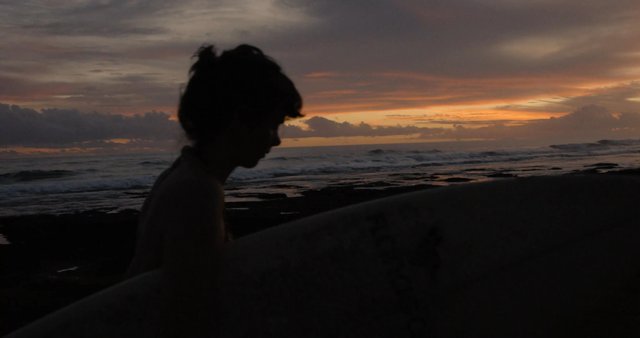 Surfer girl's silhouette at sunset