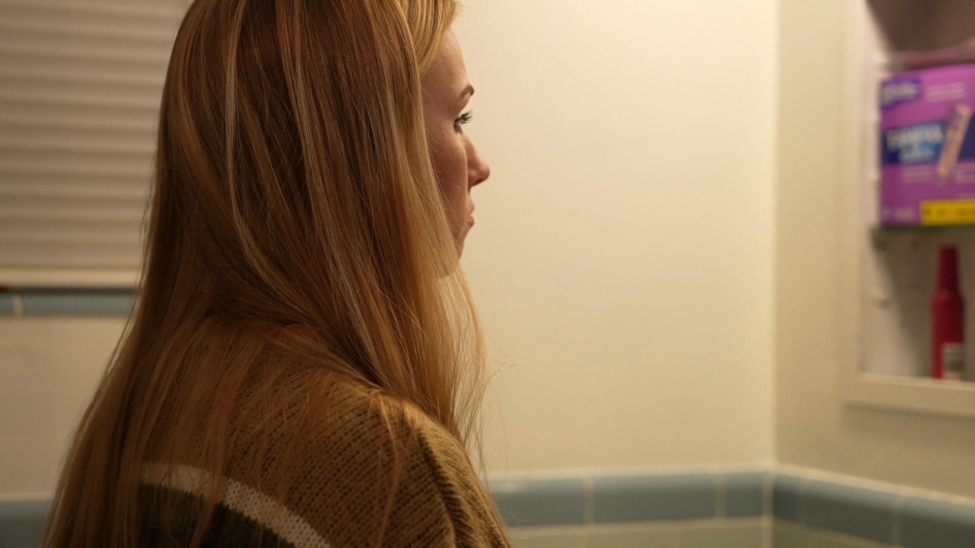 A woman tends to her personal care routine in a tiled bathroom before transitioning to sleep in her bedroom. The sequence highlights her quiet preparation for rest.