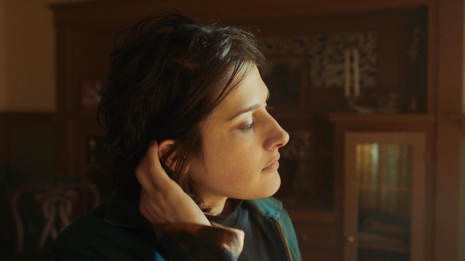 Characters engage in a tense, emotionally charged interaction within a vintage living space, marked by moments of physical distress and interpersonal friction.