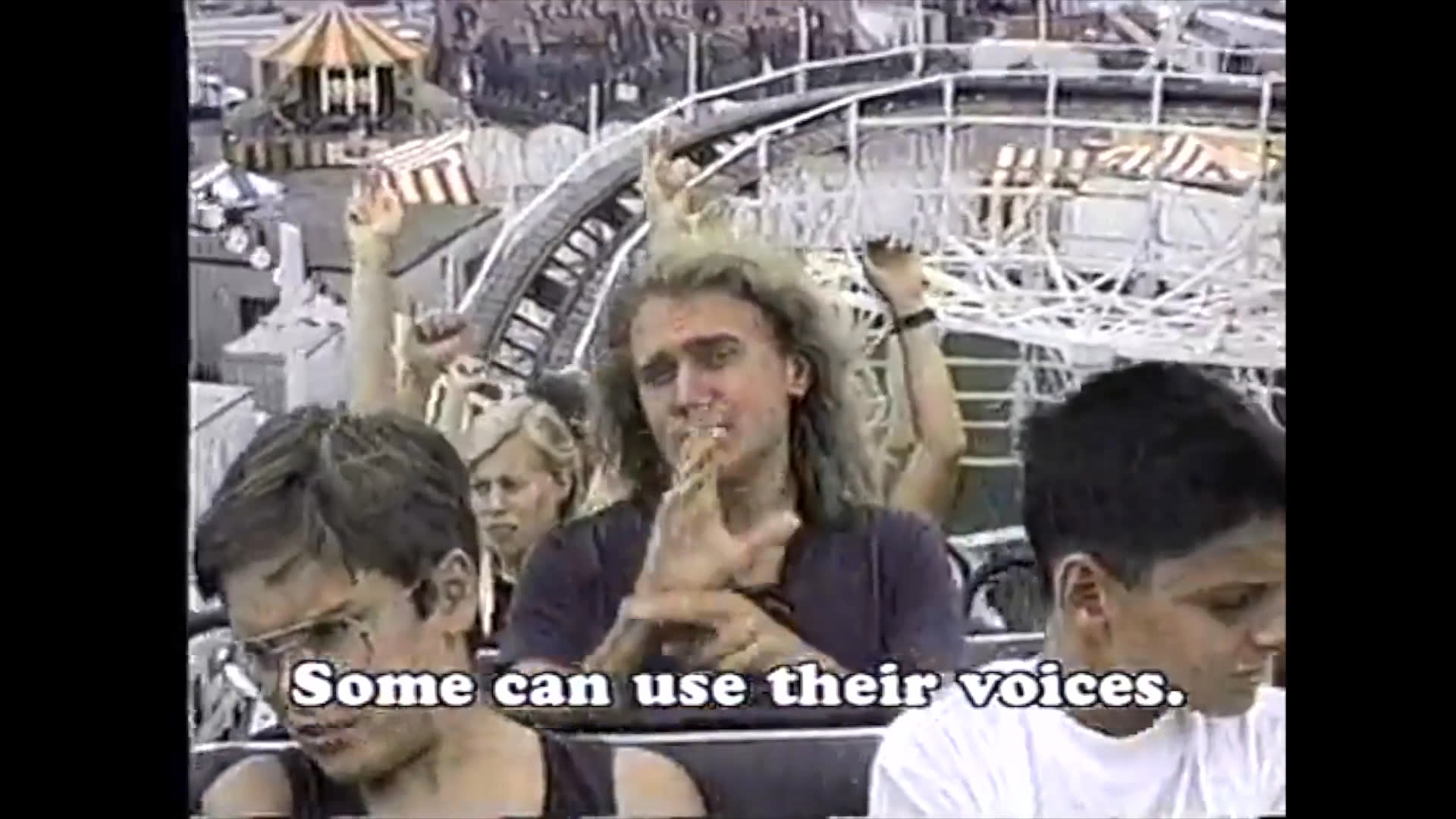 A diverse group of individuals enjoys a rollercoaster ride while emphasizing the various ways people communicate, including sign language and lip-reading, to celebrate human differences.