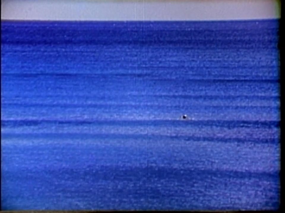 A surfer paddles out into the open ocean before catching and riding a wave in a coastal Hawaiian setting. The footage showcases traditional surfing techniques and the natural beauty of the Pacific waters.