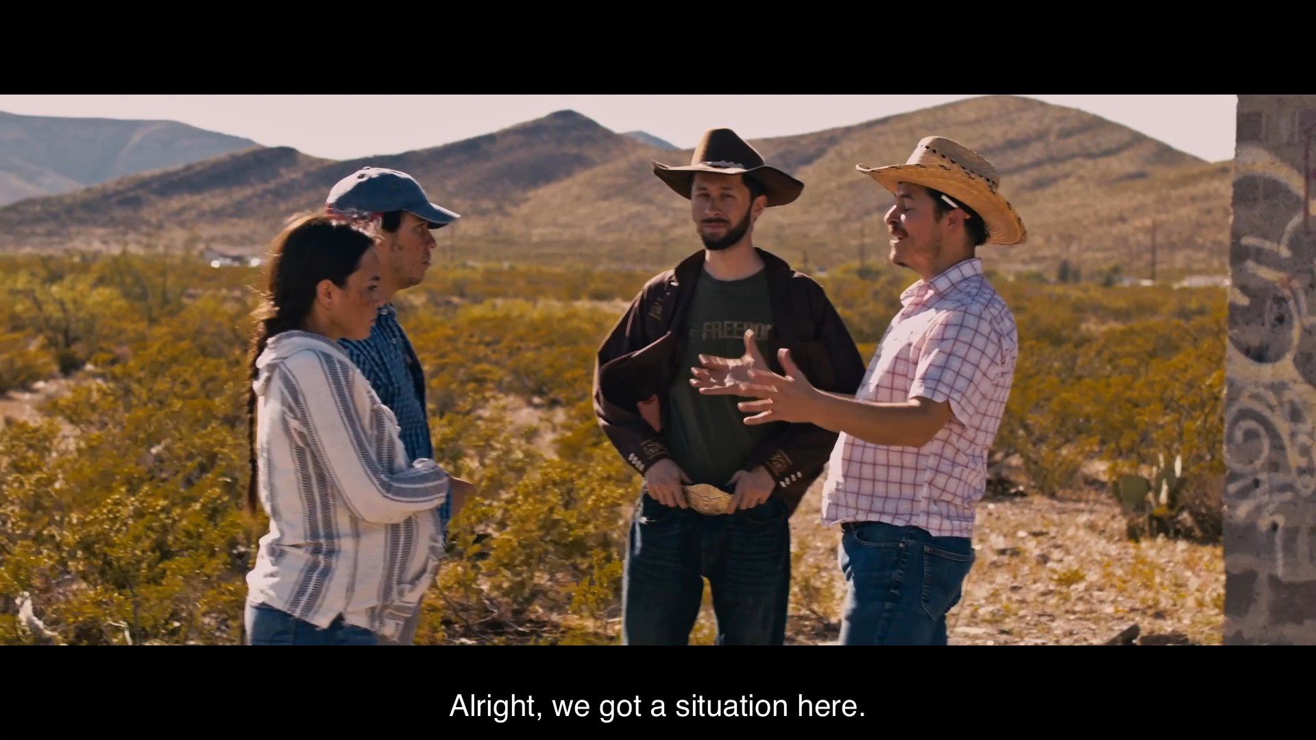 A group of individuals in a desert setting engages in a tense standoff over a theft accusation.