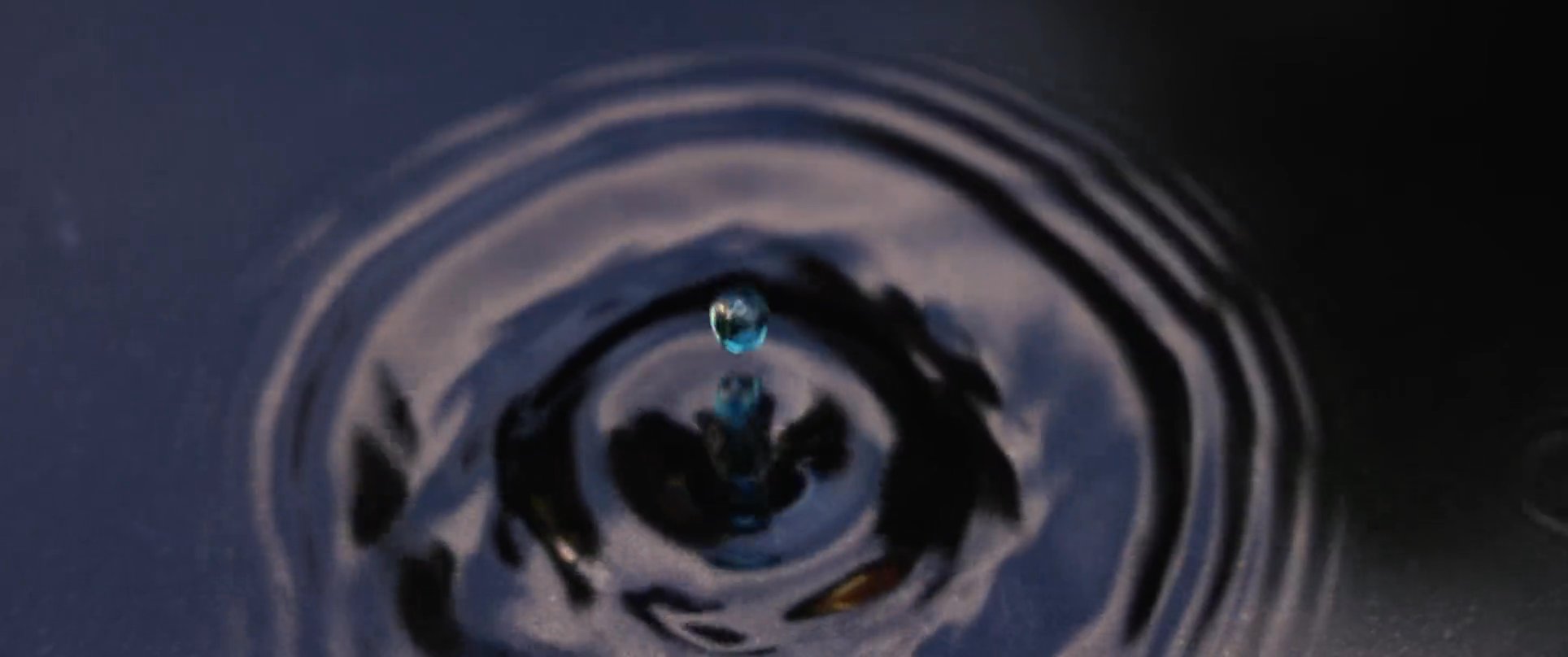 A man meditates in a peaceful outdoor setting, followed by rhythmic ripples in a pool of water as a reflection of his calm state. The scene emphasizes a quiet moment of mindfulness and environmental harmony.