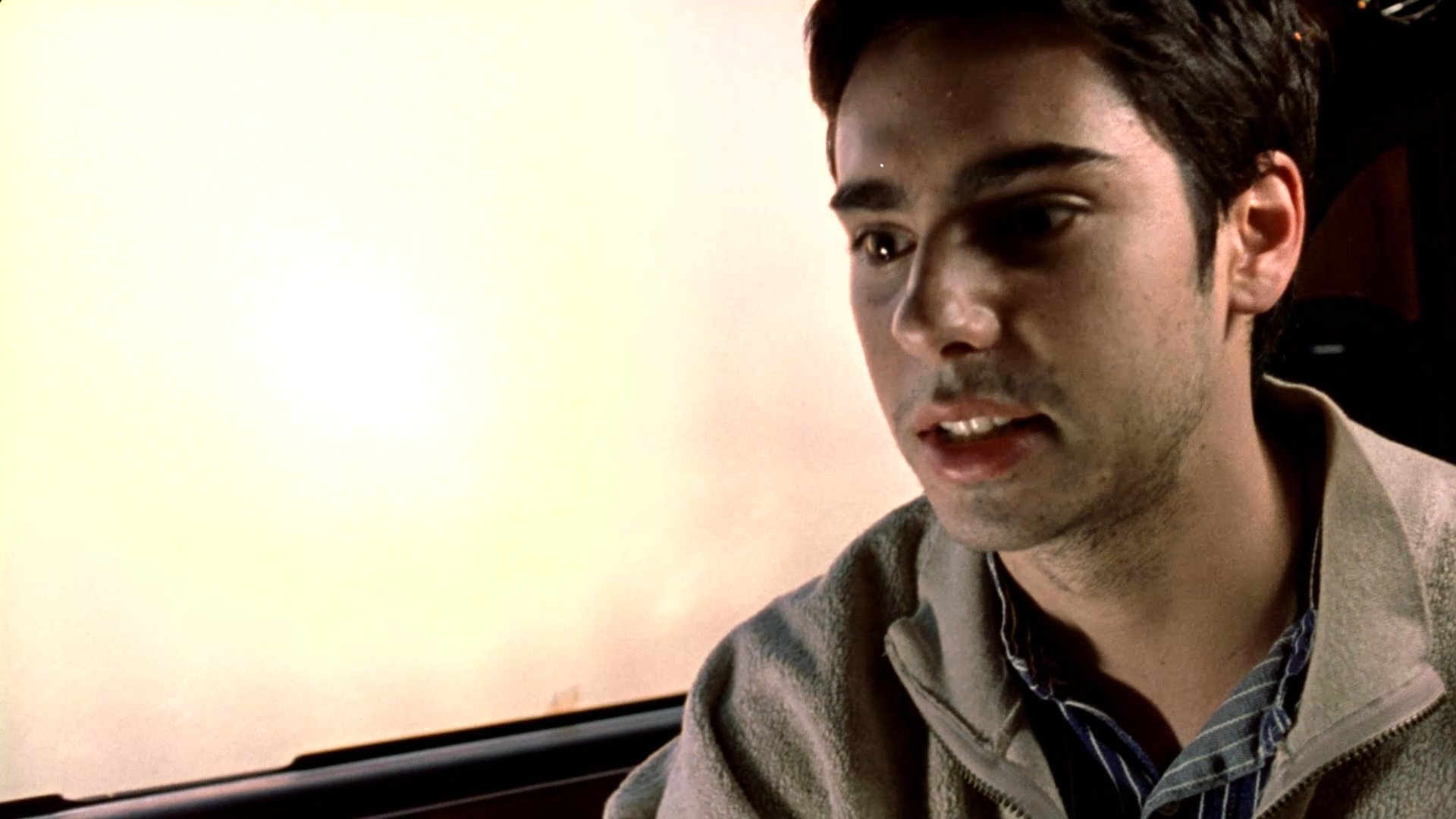 Two individuals engage in a tense conversation while riding in the back seat of a limousine. The scene captures the dynamic interaction between the passengers as they navigate a discussion during their transit.