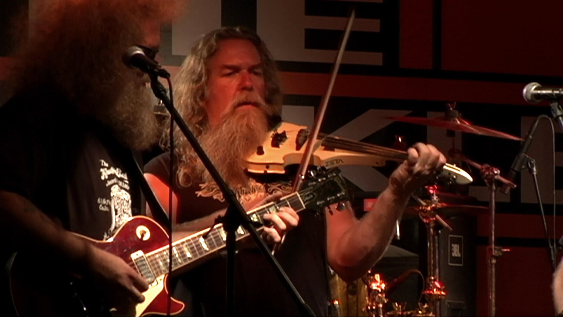 A country band performs on a nightclub stage while an audience dances to the live music.