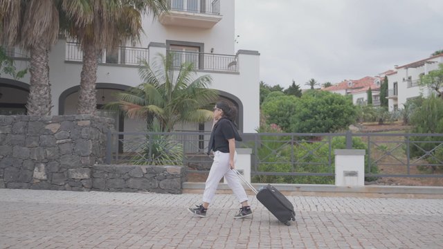 A woman walking with a suitcase to the hotel