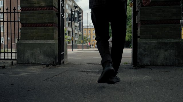 A man walks out of the park with his dog on a leash