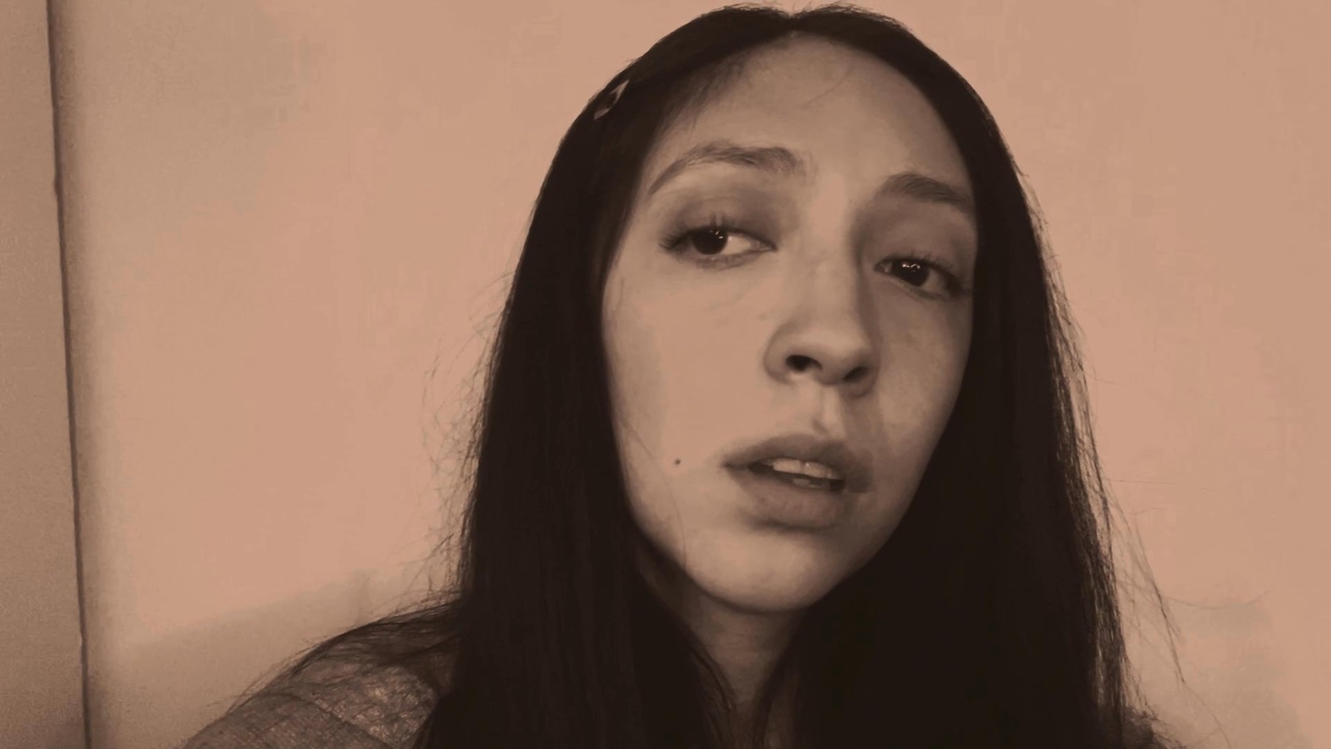 A woman delivers a serious monologue, maintaining a contemplative and expressive demeanor while addressing an unseen audience.