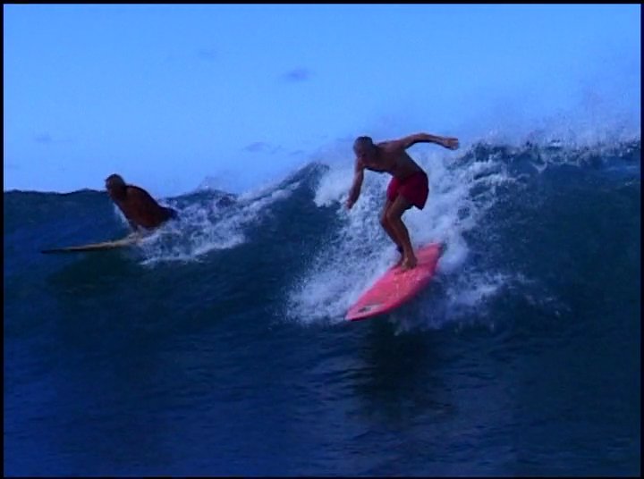 An experienced surfer expertly maneuvers a longboard across cresting ocean waves. After catching a ride, he navigates back toward the shore with his board.