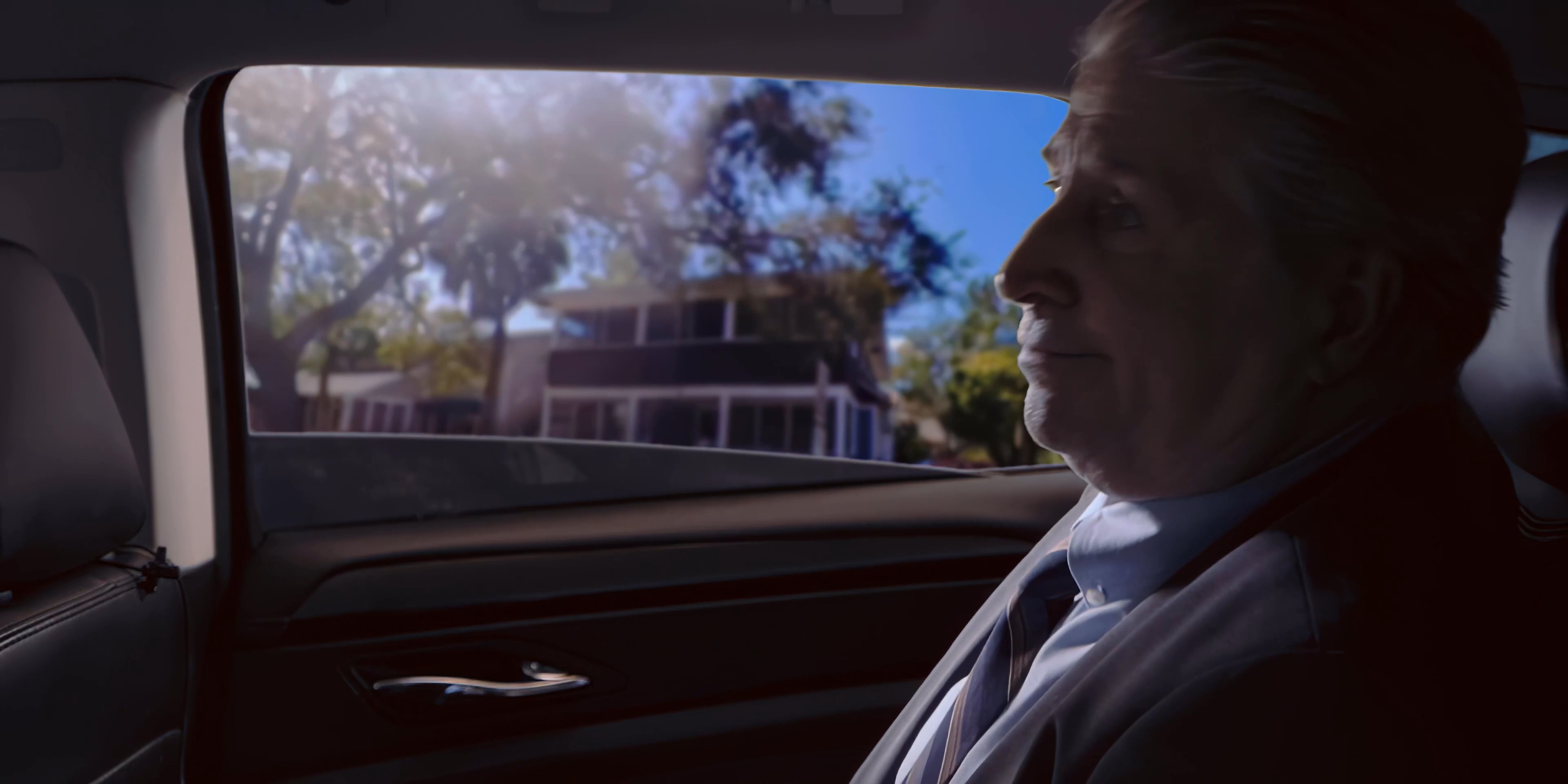 A driver operates a vehicle while a formal passenger gazes out the window during an urban drive.