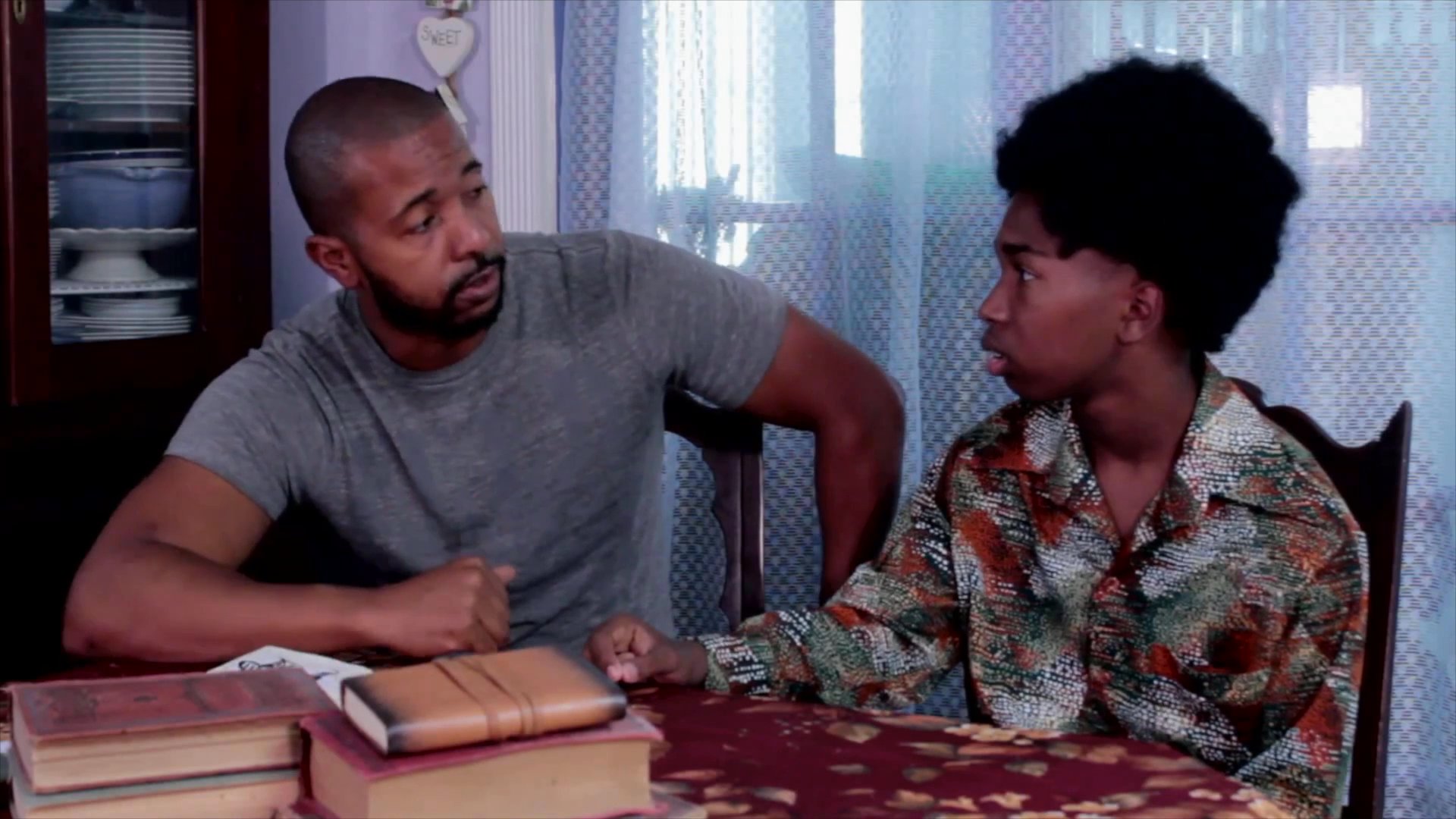 An adult mentor explains historical notes and illustrations from a journal to a young student in an educational setting.
