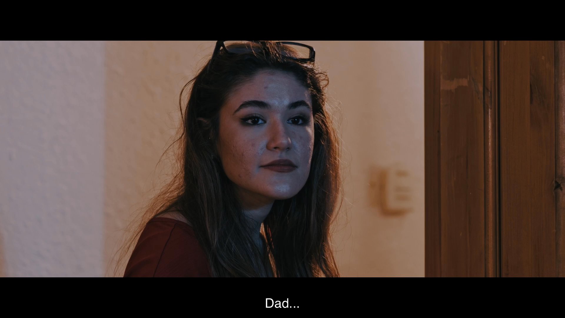 A woman engages in a gentle conversation with her father before a caregiver assists him with grooming, highlighting a moment of domestic care and family routine.