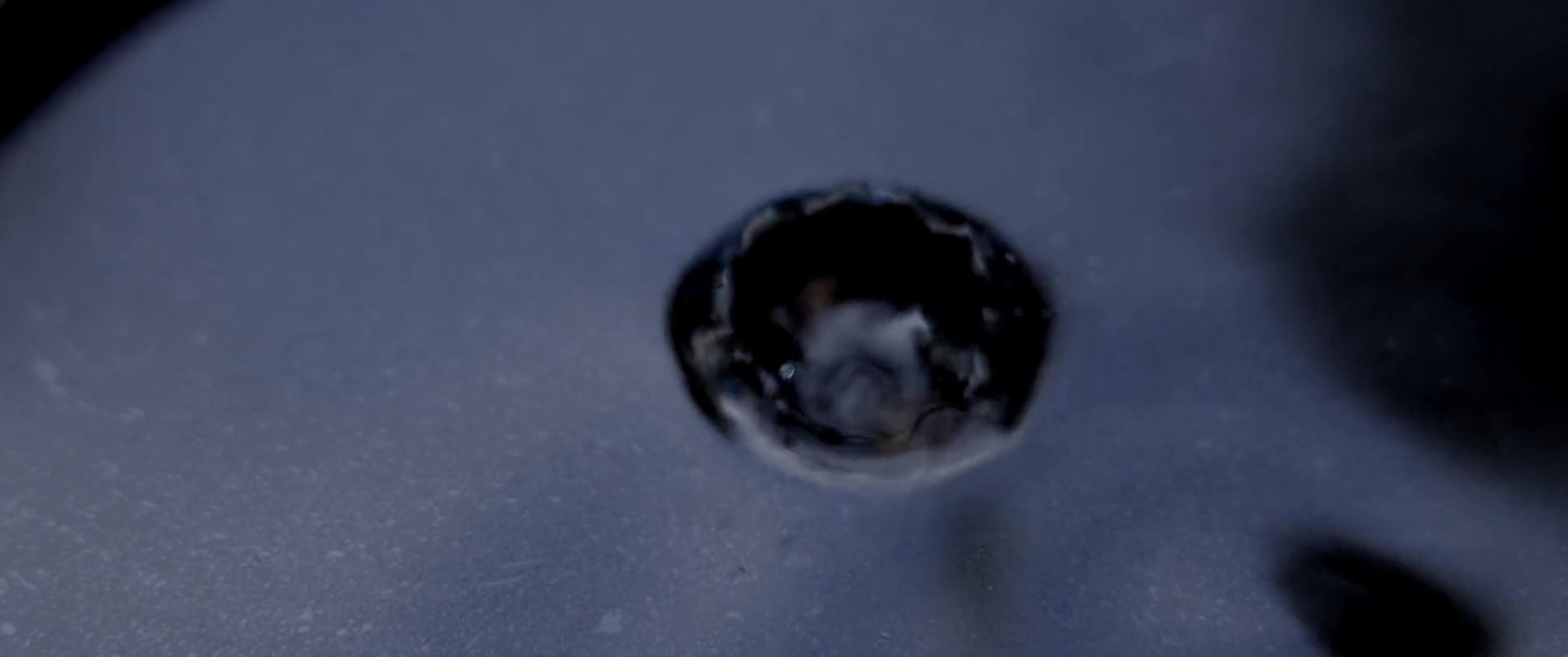 A rhythmic sequence captures a water droplet falling from a faucet, creating concentric ripples in a dark pool, followed by an intense close-up of a human eye.
