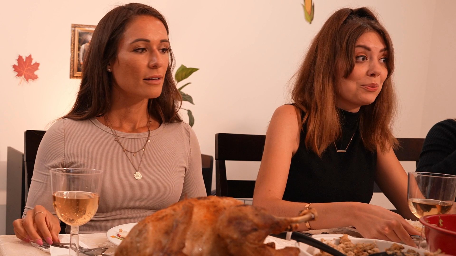 A family shares a festive holiday meal together, engaging in conversation around a dining table laden with traditional dishes.