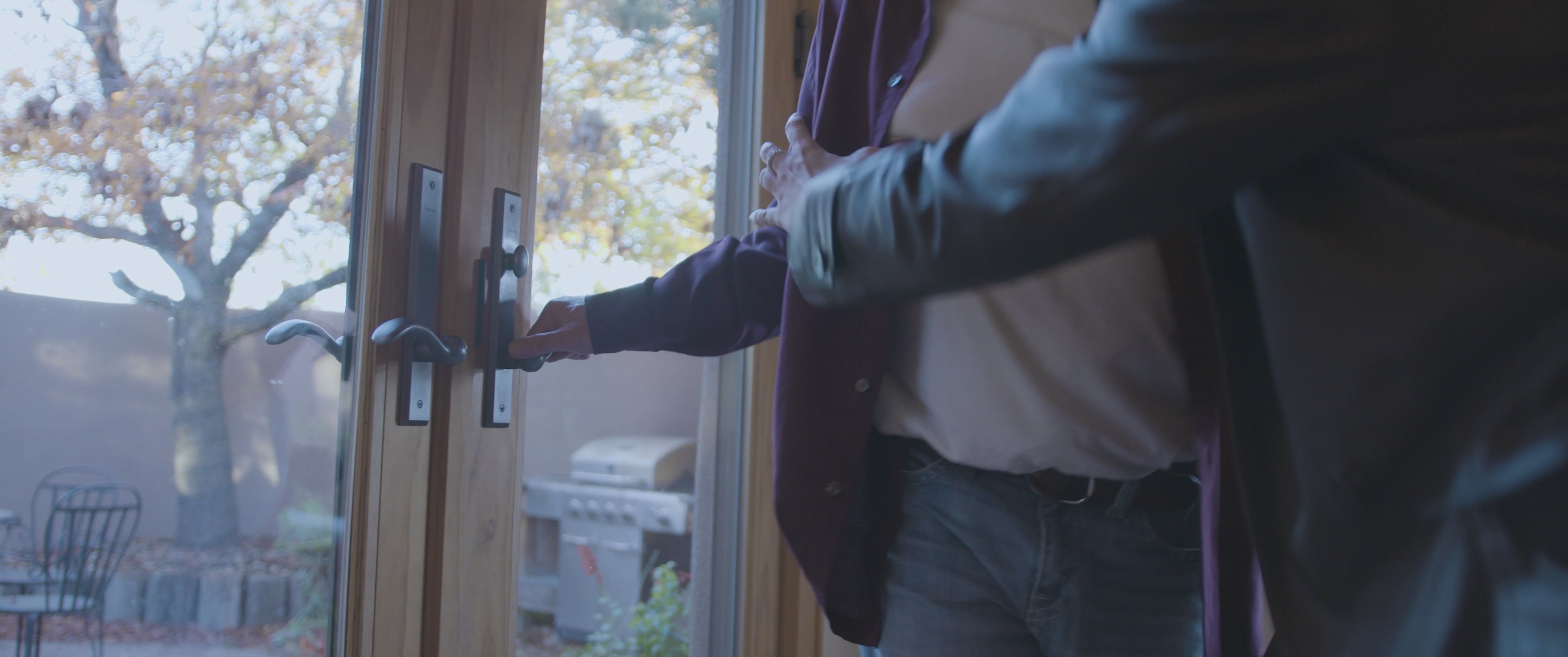 A heated argument between a man and a woman in a living room escalates into a physical confrontation, resulting in the woman being forcefully pushed to the floor.