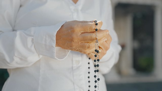 A woman is holding rosary beads